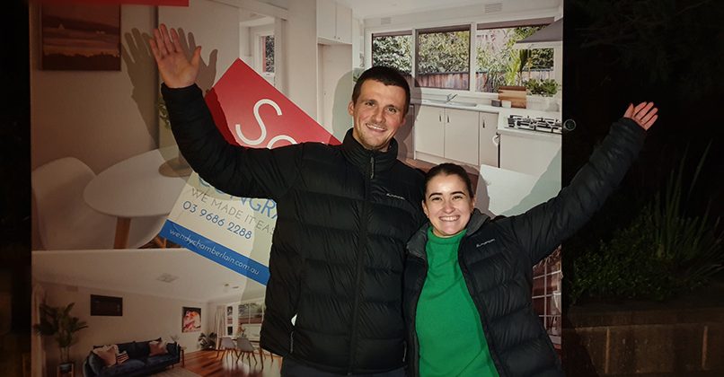 A couple infront of the property board of their recently purchased home with help of Wendy Chamberlain.